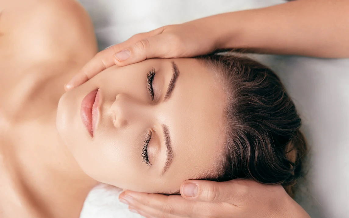 Masażystka trzymająca twarz kobiety